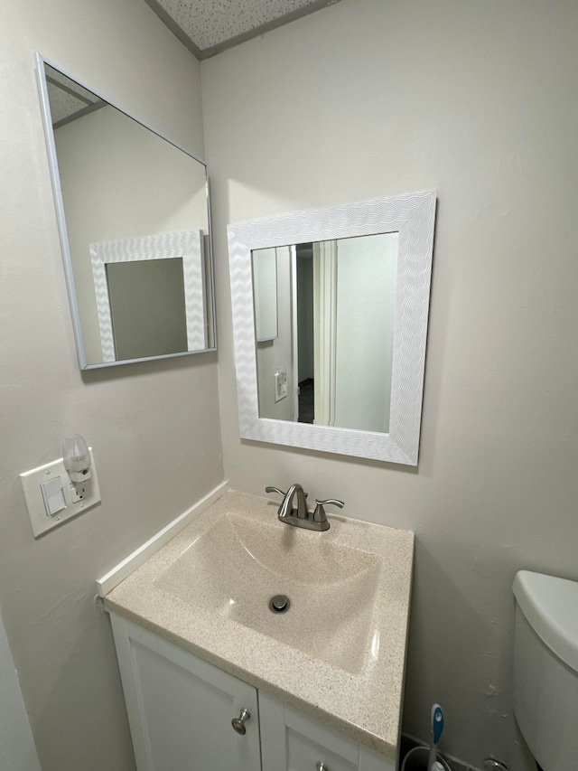 bathroom featuring a textured ceiling, vanity, and toilet