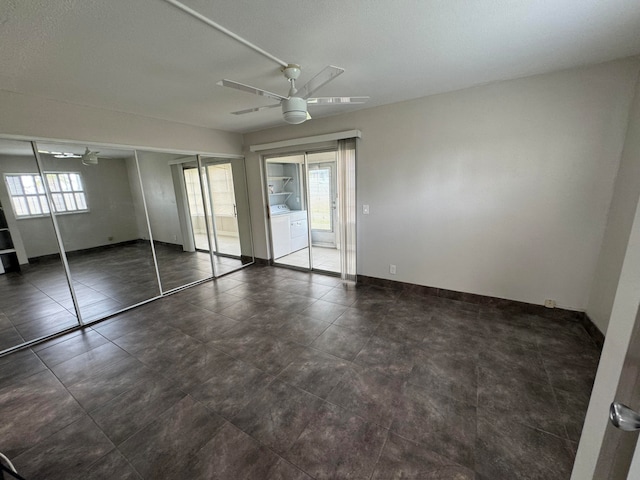 unfurnished bedroom with independent washer and dryer, ceiling fan, multiple windows, and tile patterned flooring