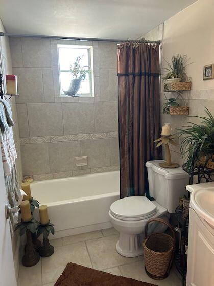 full bathroom featuring tile patterned floors, vanity, shower / bathtub combination with curtain, and toilet