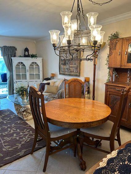 tiled dining space featuring ornamental molding and an inviting chandelier