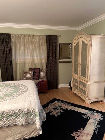 bedroom featuring ornamental molding and hardwood / wood-style flooring