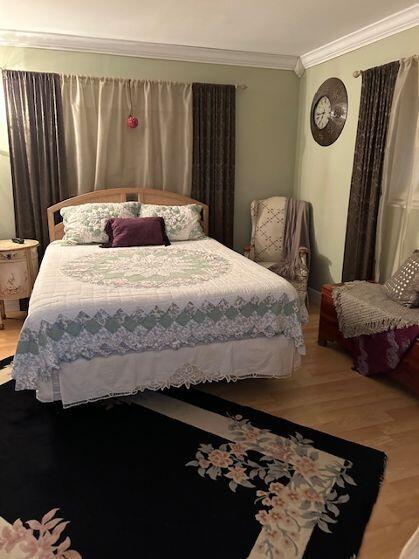 bedroom featuring crown molding and wood-type flooring