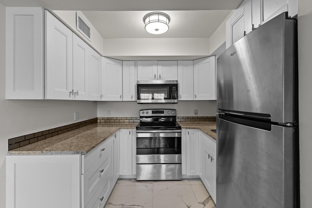 kitchen with light stone countertops, white cabinetry, and stainless steel appliances