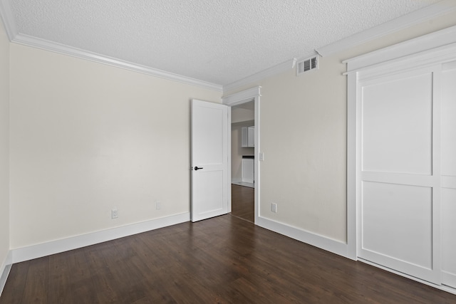 unfurnished bedroom featuring dark wood-style floors, visible vents, ornamental molding, and a textured ceiling