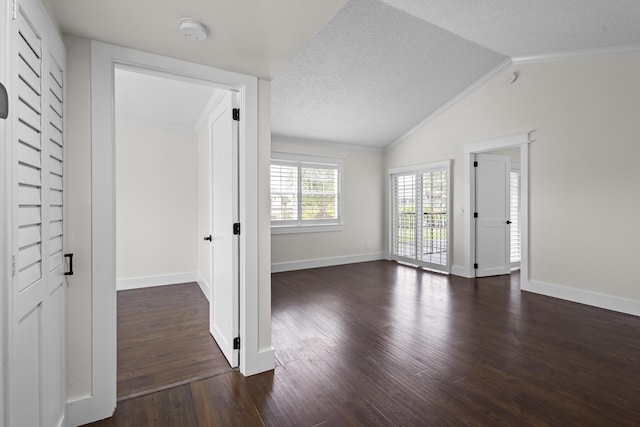 empty room featuring crown molding, dark wood-type flooring, vaulted ceiling, a textured ceiling, and baseboards