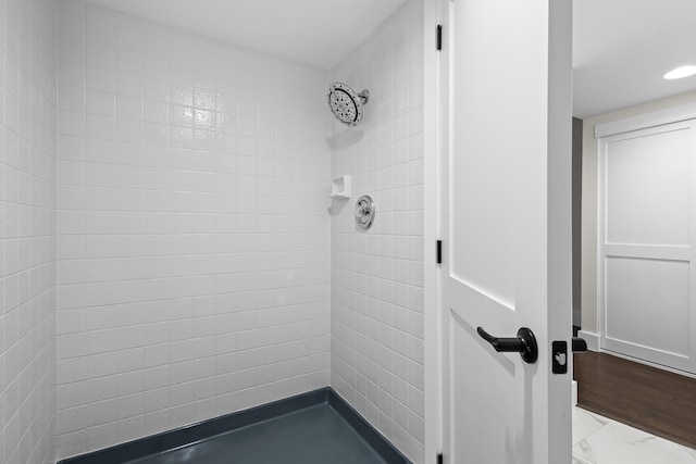 bathroom featuring marble finish floor and a tile shower