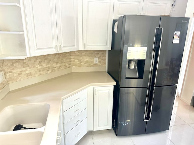 kitchen with refrigerator with ice dispenser, decorative backsplash, white cabinetry, and light tile patterned floors