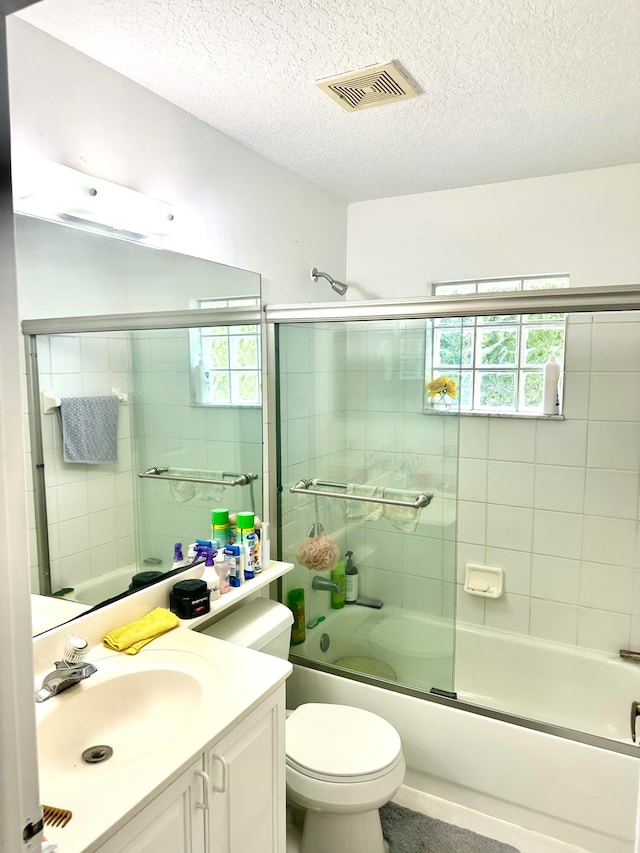 full bathroom featuring vanity, toilet, enclosed tub / shower combo, and a textured ceiling