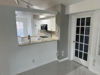 kitchen with stove, white cabinetry, sink, and concrete flooring