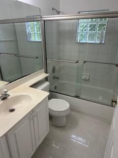 full bathroom featuring vanity, bath / shower combo with glass door, and toilet