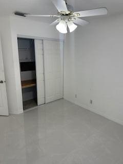 unfurnished bedroom with ceiling fan and a closet