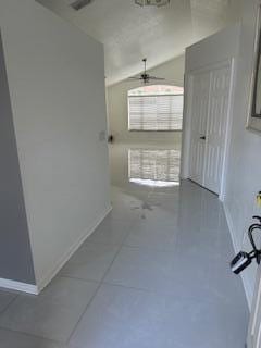 hall with tile patterned floors and vaulted ceiling