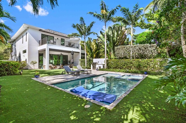 rear view of house with a fenced in pool, a yard, a balcony, and a patio