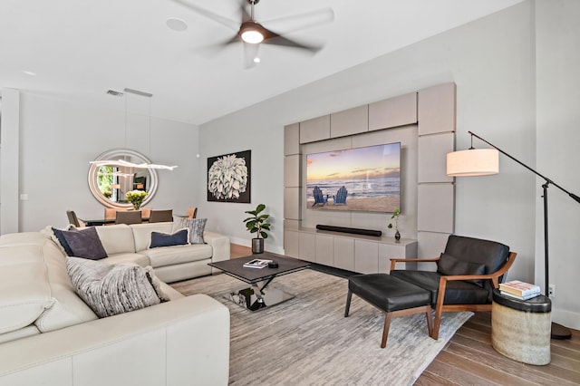 living room with visible vents, ceiling fan, baseboards, and wood finished floors