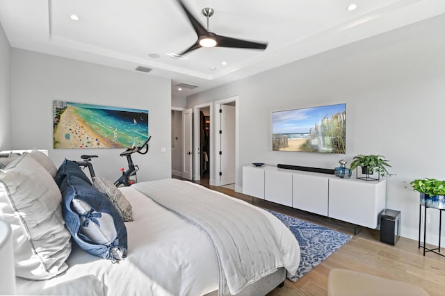 bedroom featuring light wood-style flooring, recessed lighting, visible vents, a ceiling fan, and a raised ceiling