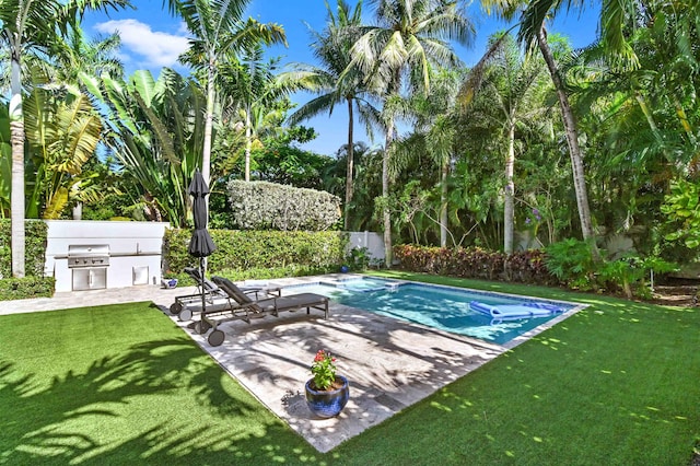 view of swimming pool with an outdoor kitchen, fence, a yard, a patio area, and a pool with connected hot tub