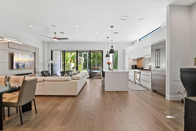 living room with ceiling fan, sink, and light wood-type flooring