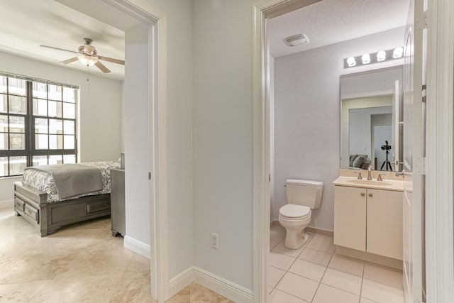 bathroom with ceiling fan, tile patterned flooring, vanity, a textured ceiling, and toilet