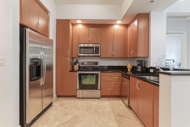 kitchen with sink, stainless steel appliances, dark stone counters, and a textured ceiling