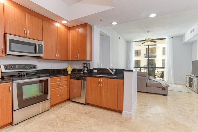 kitchen featuring sink, dark stone countertops, ceiling fan, kitchen peninsula, and stainless steel appliances