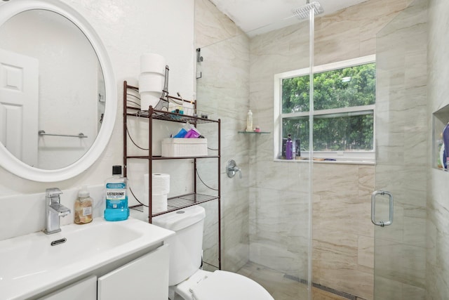 bathroom with a shower with shower door, vanity, and toilet