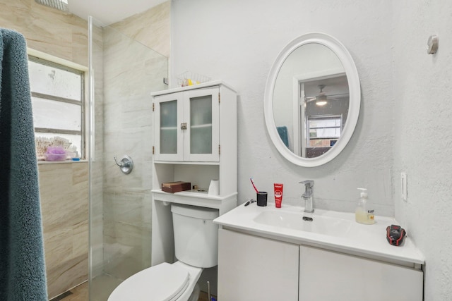 bathroom with a shower with shower door, vanity, toilet, and plenty of natural light