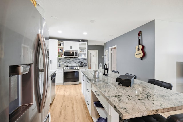 kitchen featuring a breakfast bar area, stainless steel appliances, a center island, and white cabinets