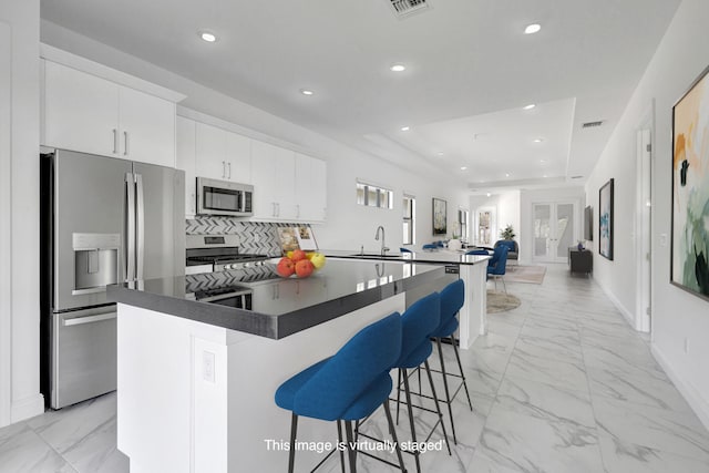 kitchen featuring a kitchen breakfast bar, white cabinetry, a kitchen island, and appliances with stainless steel finishes