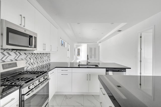 kitchen with backsplash, white cabinetry, sink, and appliances with stainless steel finishes