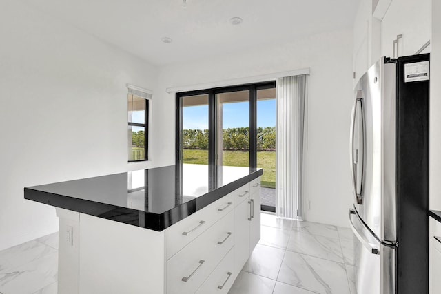 kitchen featuring white cabinets and stainless steel refrigerator