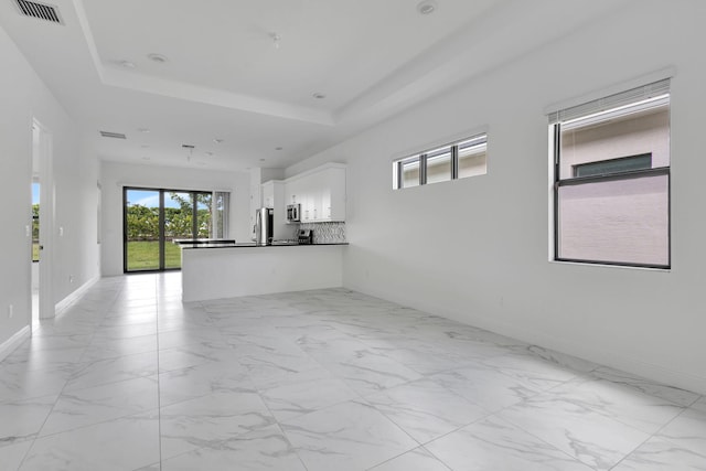 unfurnished living room with a tray ceiling