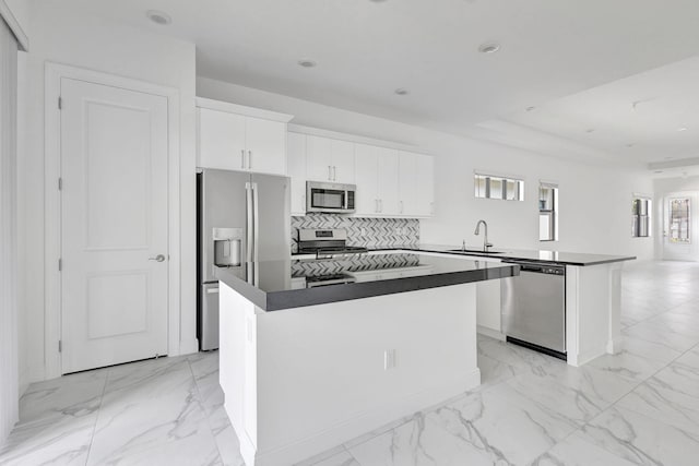 kitchen with a kitchen bar, white cabinetry, a center island, and stainless steel appliances