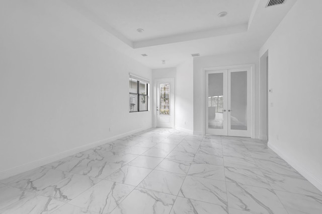 unfurnished room featuring a tray ceiling and french doors