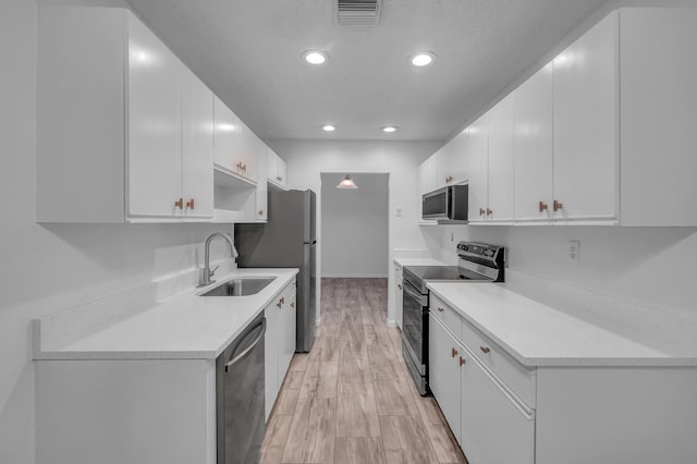 kitchen with light wood-type flooring, white cabinets, stainless steel appliances, and sink