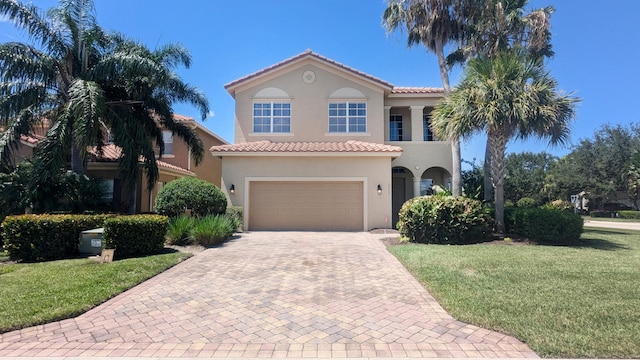 mediterranean / spanish home featuring a front yard and a garage