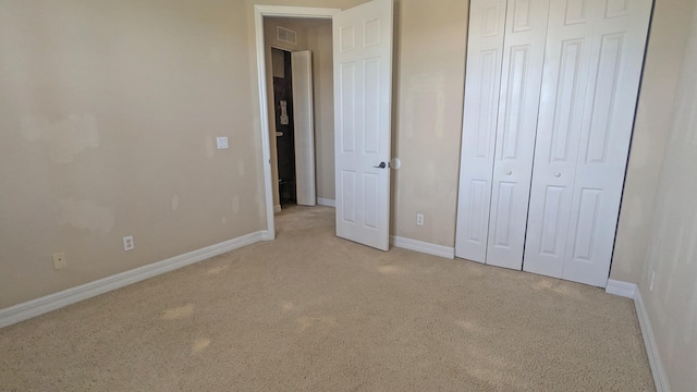 unfurnished bedroom featuring a closet and light carpet