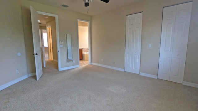 unfurnished bedroom featuring multiple closets, light colored carpet, and ceiling fan