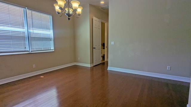 spare room with a notable chandelier and dark hardwood / wood-style floors