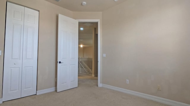 unfurnished bedroom with light colored carpet and a closet