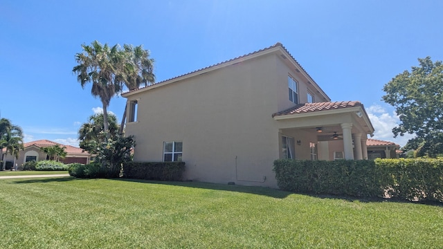 view of property exterior with ceiling fan and a lawn