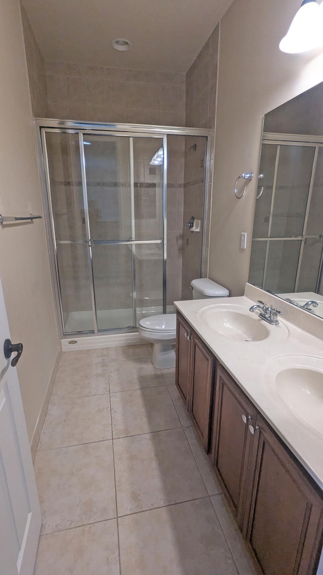 bathroom with vanity, a shower with shower door, toilet, and tile patterned flooring