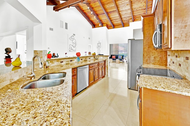 kitchen with light stone counters, sink, high vaulted ceiling, and appliances with stainless steel finishes