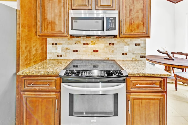 kitchen featuring tasteful backsplash, light tile patterned flooring, light stone countertops, and appliances with stainless steel finishes