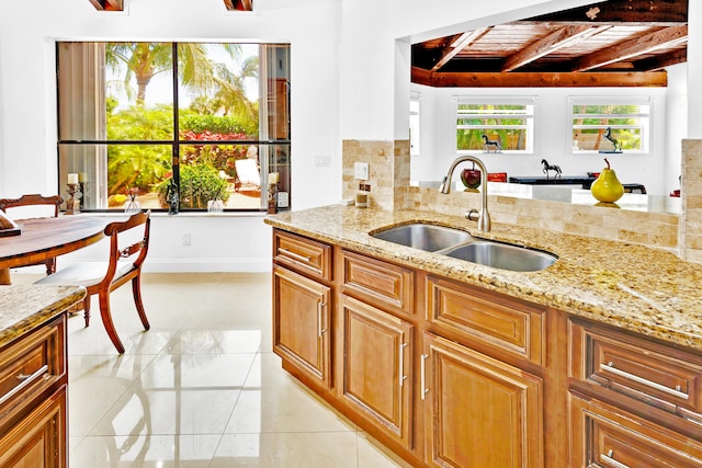 kitchen featuring beamed ceiling, light stone countertops, sink, and wooden ceiling