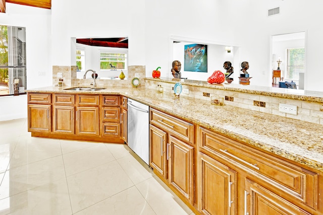 kitchen with dishwasher, sink, light tile patterned floors, kitchen peninsula, and light stone countertops