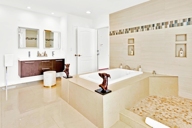 bathroom with vanity, tile patterned floors, tiled bath, and tile walls