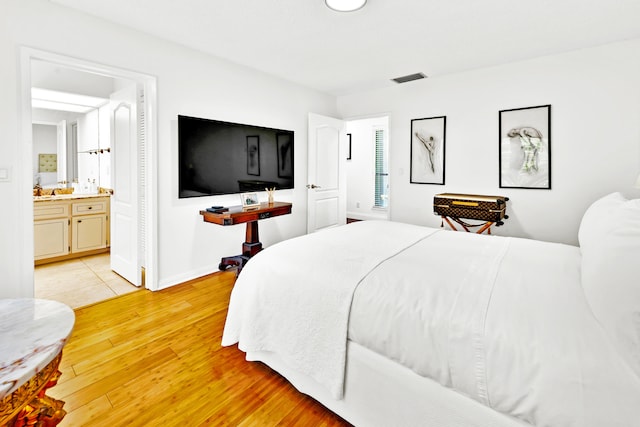 bedroom with ensuite bath and light hardwood / wood-style flooring