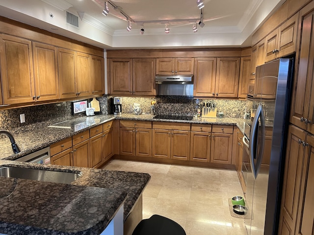 kitchen with decorative backsplash, rail lighting, dark stone countertops, and stainless steel fridge