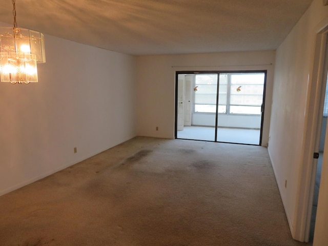 carpeted empty room with a chandelier