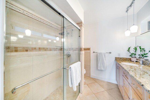 bathroom with toilet, vanity, a shower with shower door, and tile patterned flooring